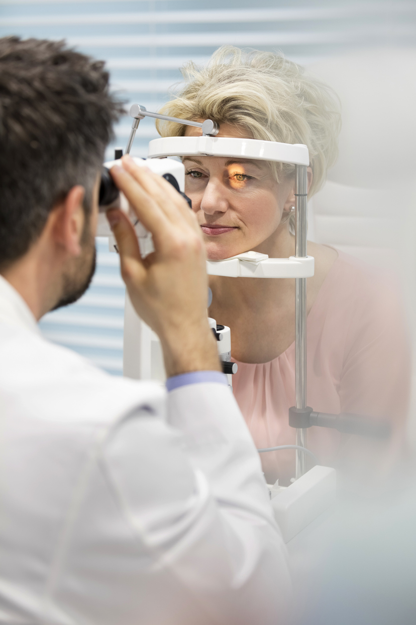 Optometrist examining mature patient on phoropter at hospital